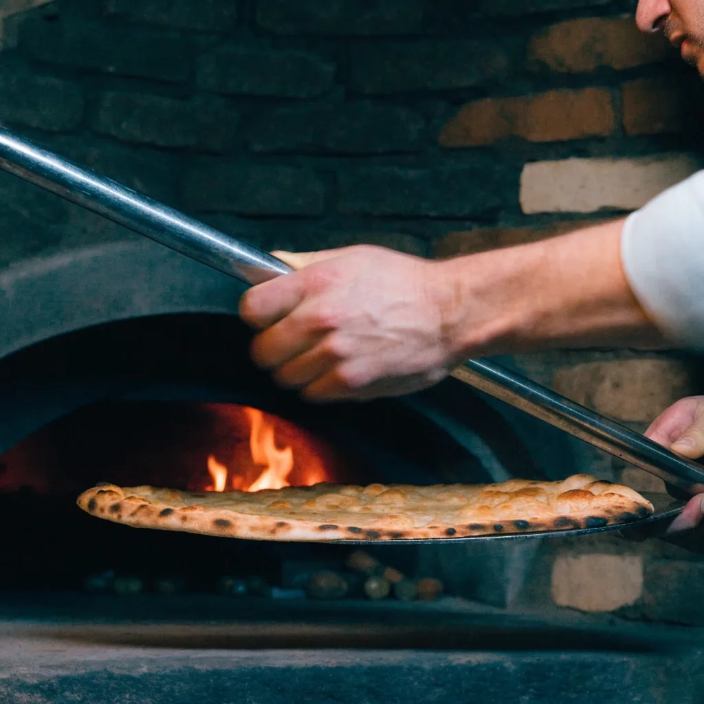 Coal oven baking a thin pizza at high heat